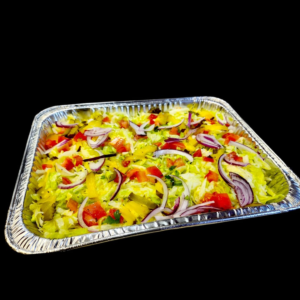 A large aluminum tray filled with a fresh salad of lettuce, red onions, tomatoes, and yellow peppers.